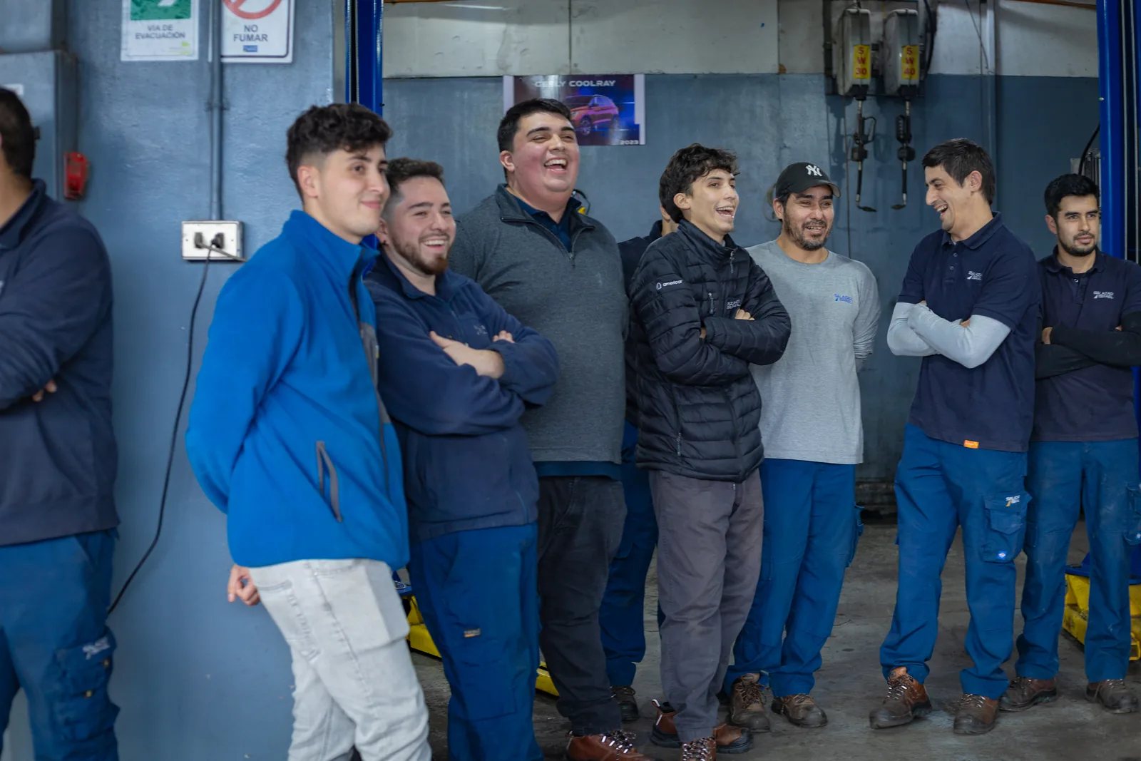 Trabajadores de un taller riendo durante una charla de prevención de riesgos con magia.